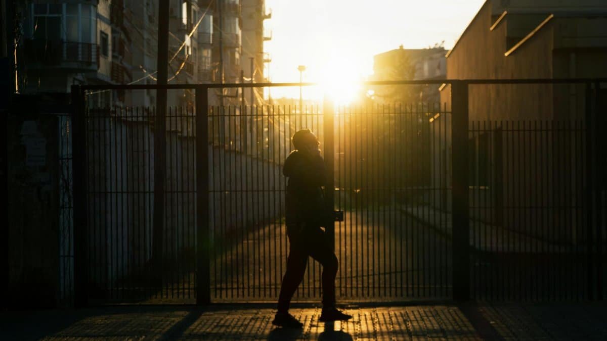 Silhouette of a person walking by a gate during sunset in Tirana, Albania.