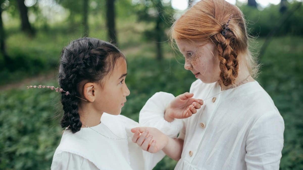 Two girls making a pinky promise in a sunlit park, capturing the essence of childhood friendship.