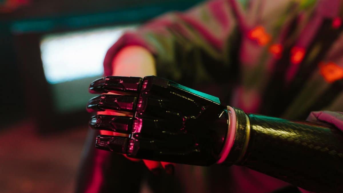 A close-up view of a futuristic bionic prosthetic arm in neon lighting.