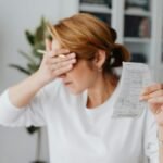 Woman experiencing stress while reviewing household expenses at home.