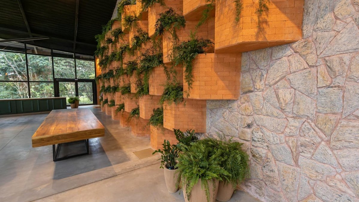 Spacious modern interior featuring brick walls with greenery and wooden table.