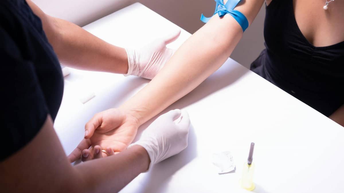 Healthcare professional performing blood sampling for medical testing with a focus on disease prevention.