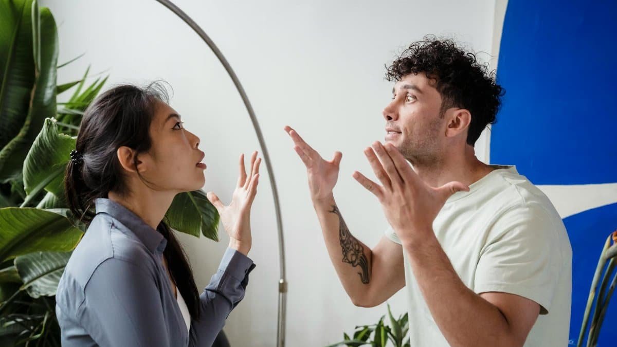 A couple argues indoors amidst greenery, showcasing emotions and interpersonal conflict.