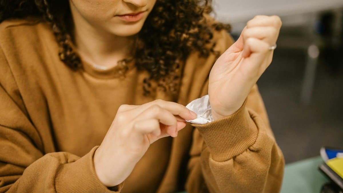 Close-up of a student using a hidden cheat sheet on their wrist during an exam, indoors.