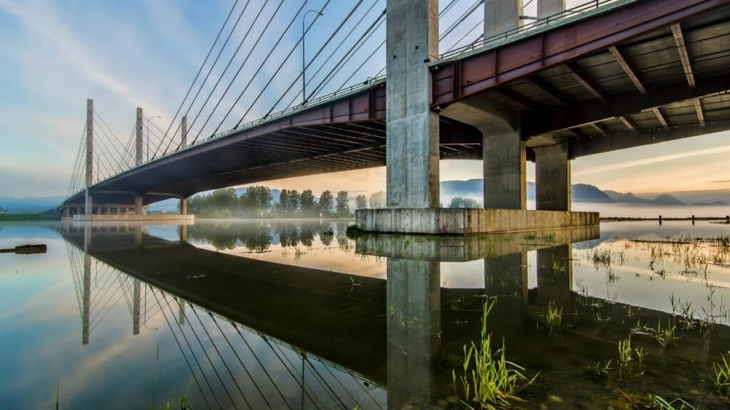 Peaceful reflection of Pitt River Bridge in Pitt Meadows, BC, during sunrise.