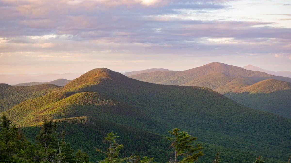 Explore the serene beauty of Vermont's green mountains during sunrise, capturing nature's peaceful essence.
