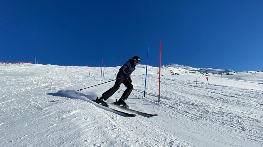 Skier skillfully navigating slalom course in snowy Les Belleville on a bright winter day.