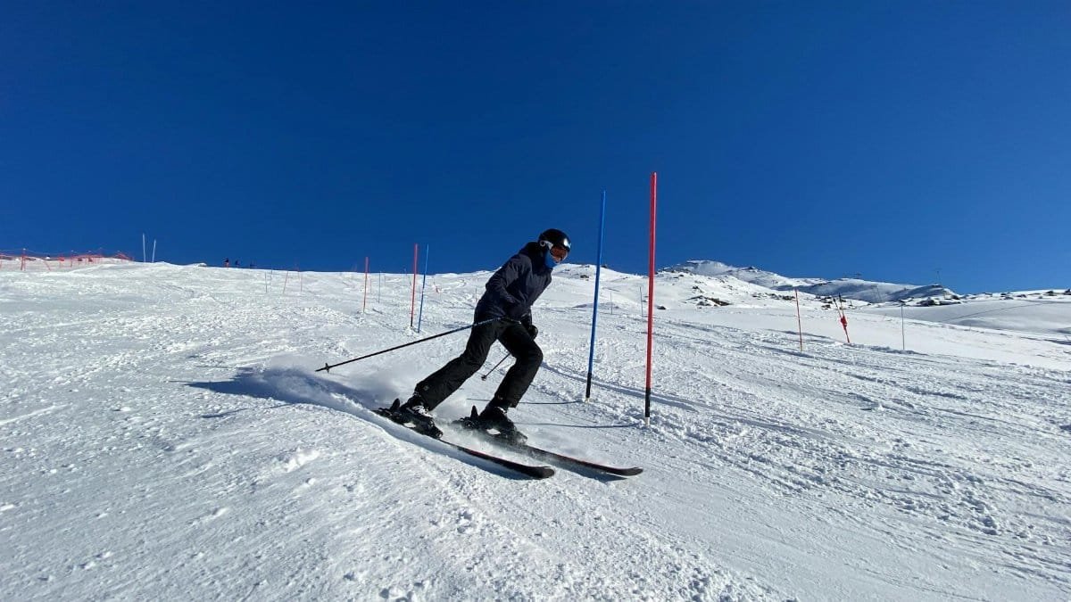 Skier skillfully navigating slalom course in snowy Les Belleville on a bright winter day.
