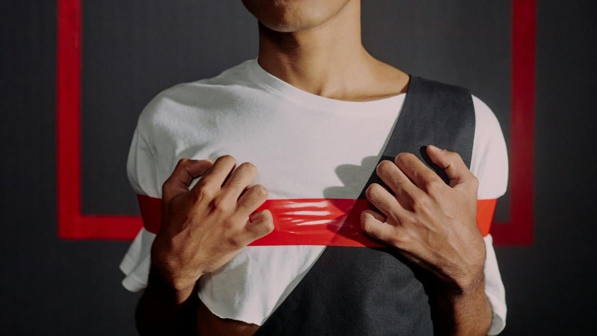 A man expresses concept of breaking stereotypes in a studio setting with red tape.