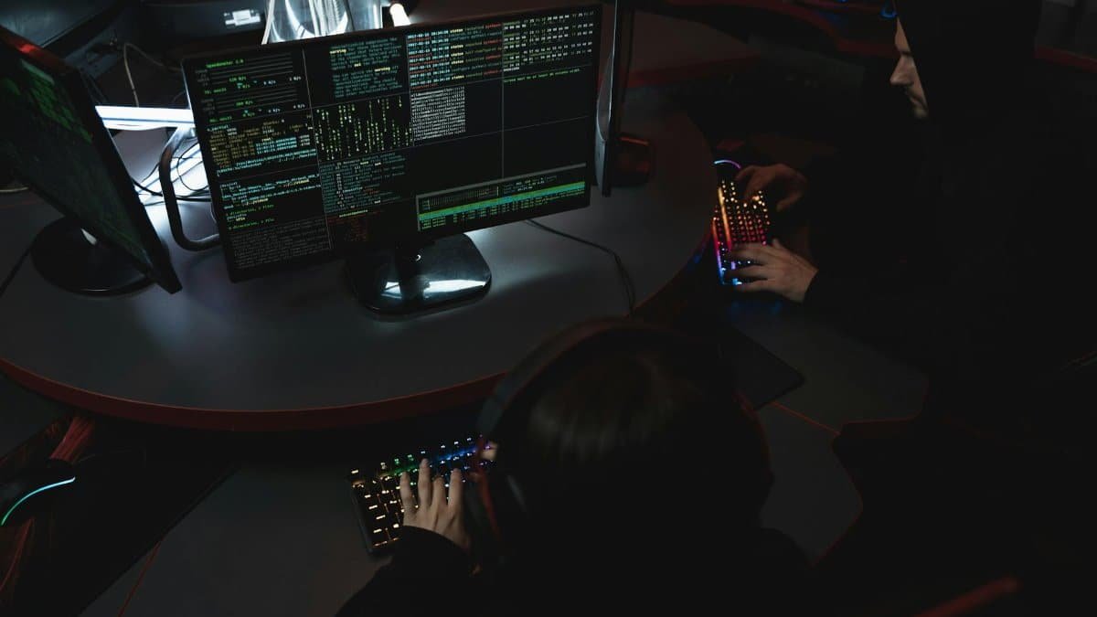 A group of people in a dark room working on computers, related to cybersecurity.
