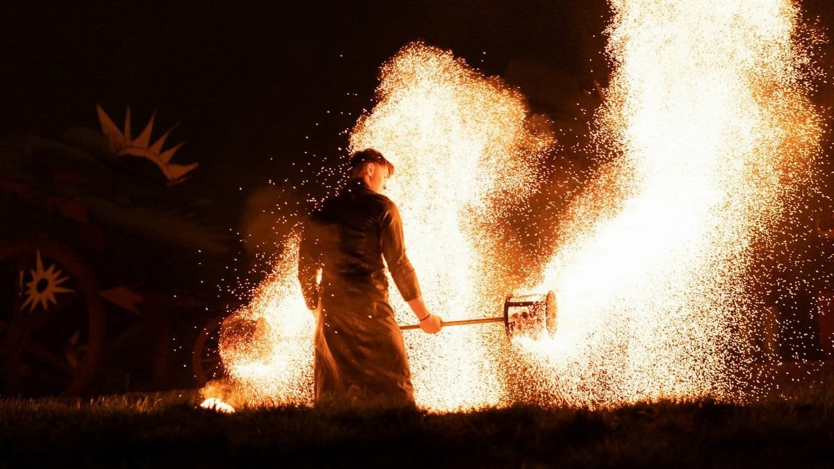 A man engaging in a dynamic fire performance, creating an intense show with sparking flames.