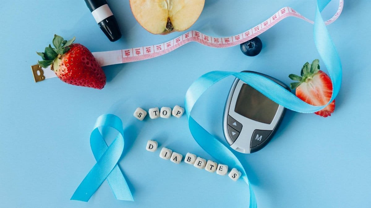Creative diabetes awareness with fruits, glucometer, and ribbon on blue background.