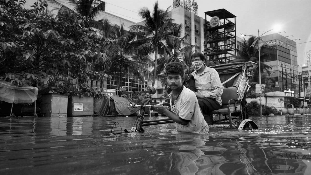 A rickshaw pulls through flooded city streets in Kolkata, India, showcasing urban life challenges.