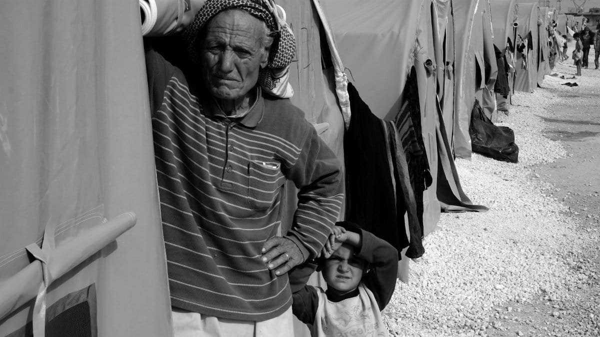 Black and white image of refugees in a camp, highlighting humanity and resilience.