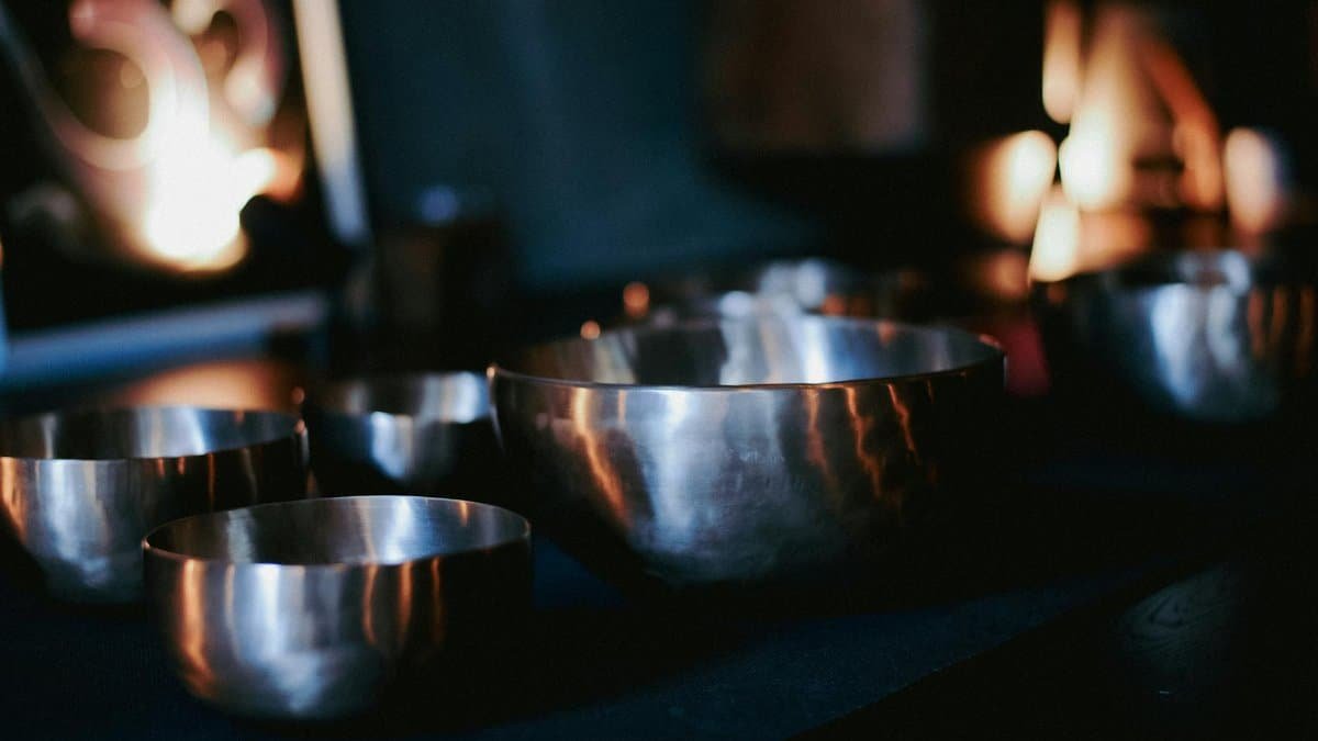 A serene scene featuring Tibetan metal singing bowls in a dimly lit room with candles.