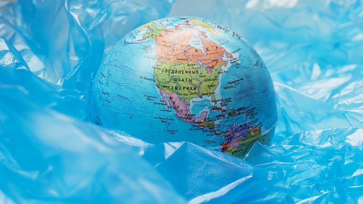 A globe surrounded by blue plastic represents global environmental issues and pollution.