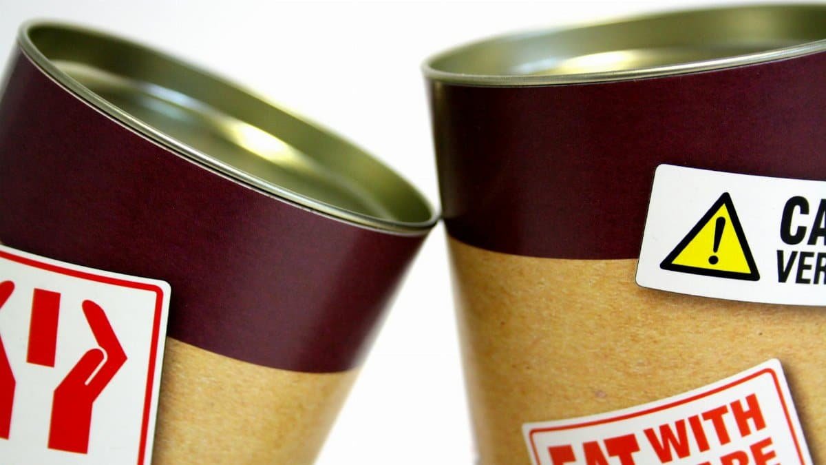 Close-up view of warning labels on canned food containers indicating caution and safety.