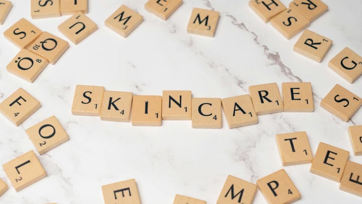Wooden letter tiles spelling 'skincare' on a marble surface, symbolizing beauty.