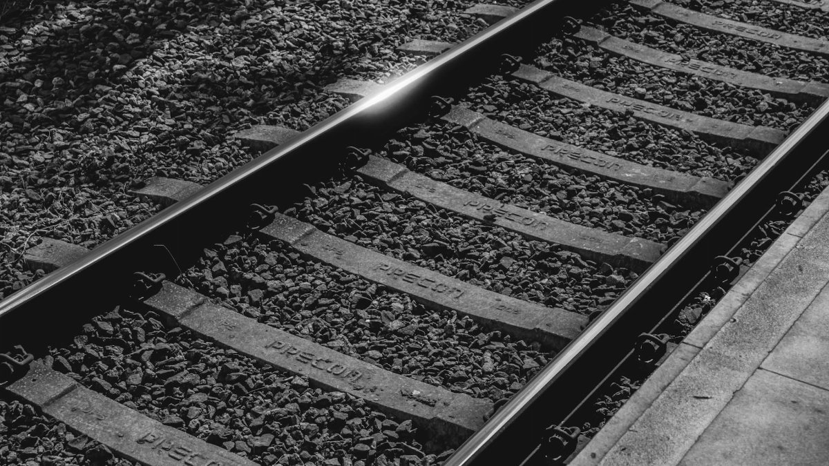 Detailed black and white view of railway tracks with gravel and sleepers.