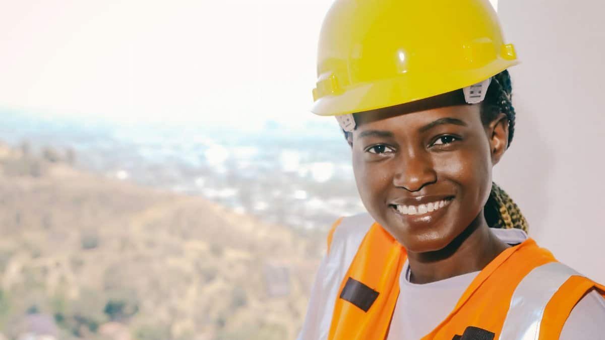 Black female engineer wearing safety gear and smiling, representing modern construction workforce.