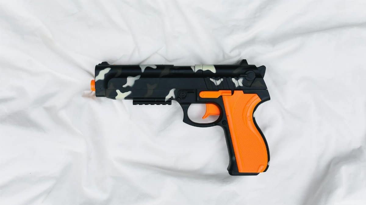 Orange and black toy gun with camouflage pattern on a white backdrop.