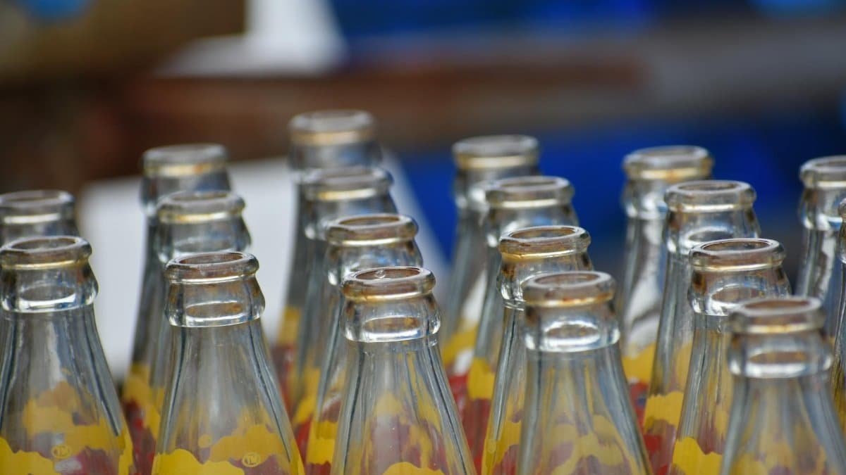 Empty glass soda bottles arranged in rows with colorful labels, perfect for recycling themes.