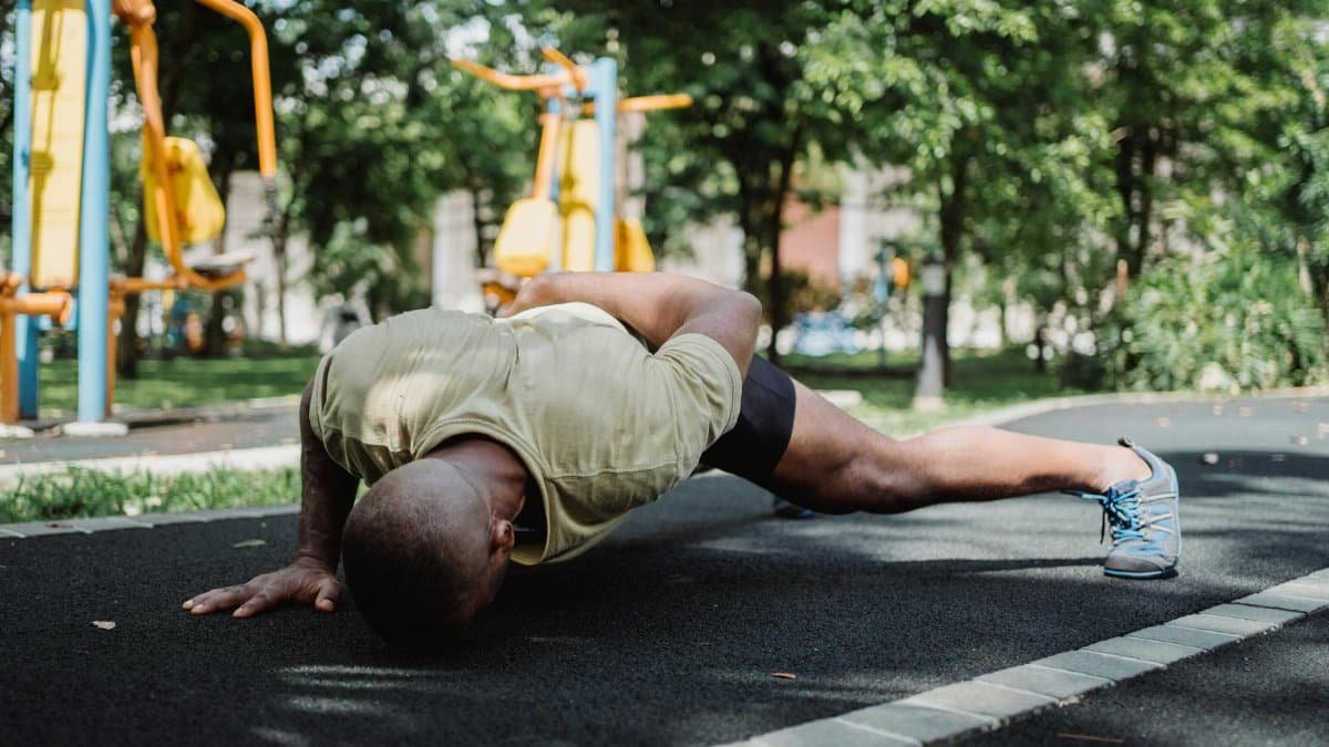 Fitness enthusiast doing push-ups on a sunny day in an urban park, showcasing strength and health.