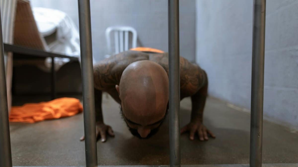 Bald man performing push-ups in a prison cell, showcasing fitness and resilience behind bars.
