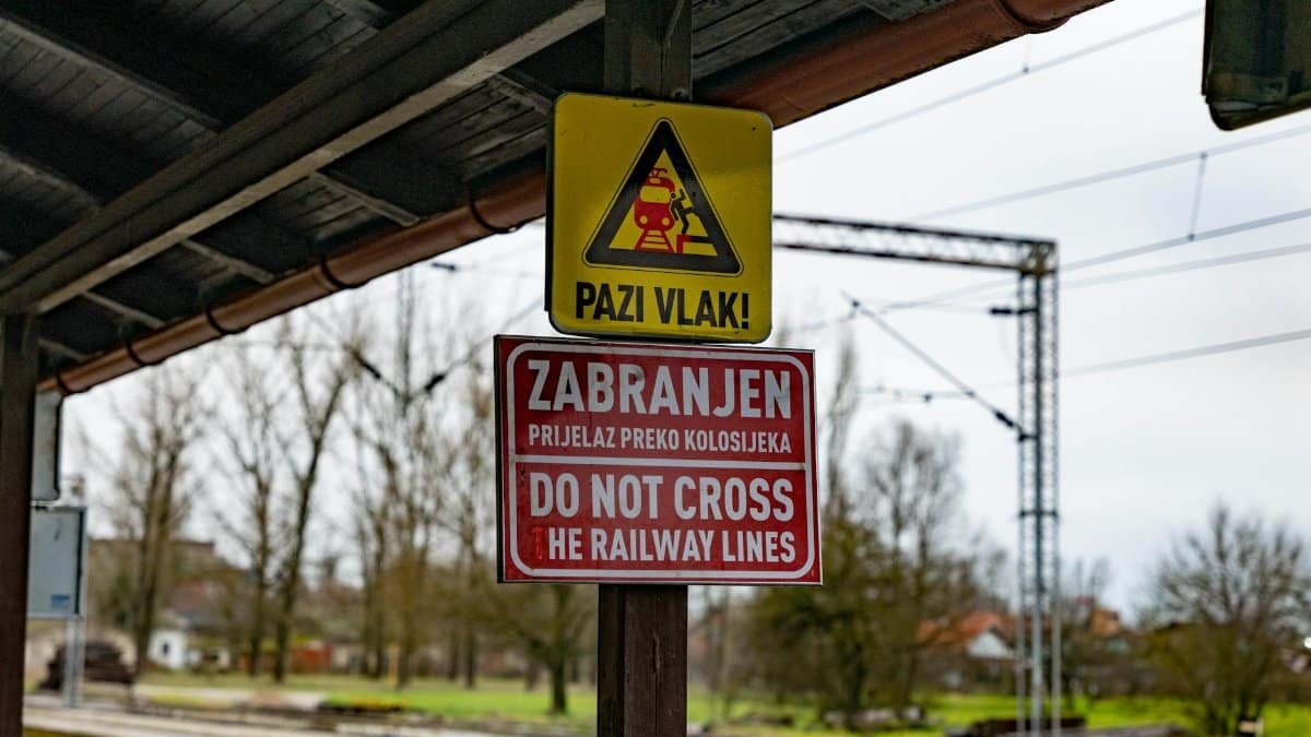 Close-up of warning and 'Do Not Cross' signs at a Croatian railway station.
