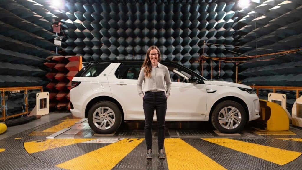 Female engineer stands in anechoic chamber with a car for sound testing.