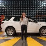Female engineer stands in anechoic chamber with a car for sound testing.