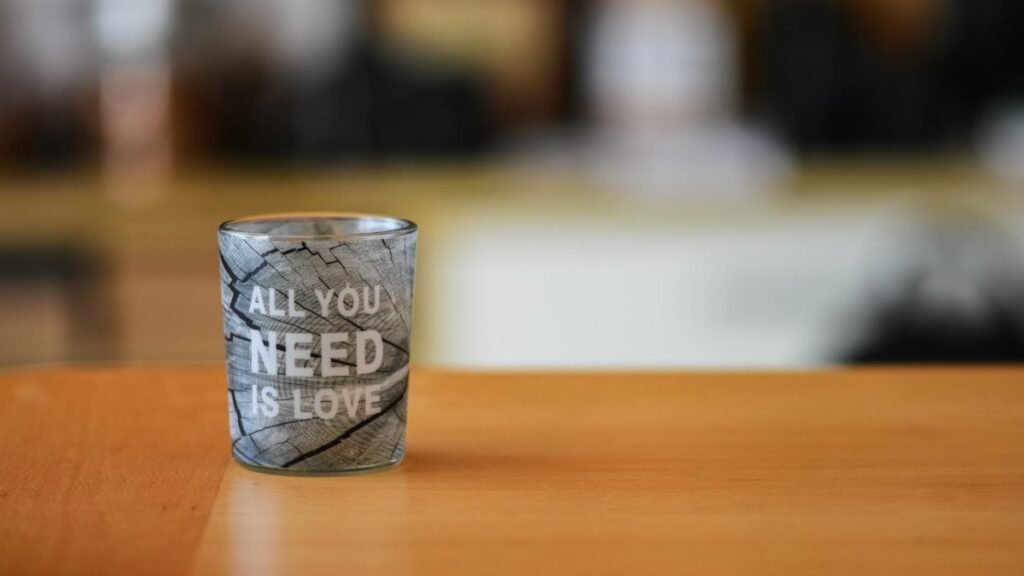 A close-up of a glass cup with 'All You Need is Love' text, ideal for lifestyle themes.