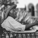Elderly man in traditional attire shakes hands in a Cholula street. Black and white portrait.