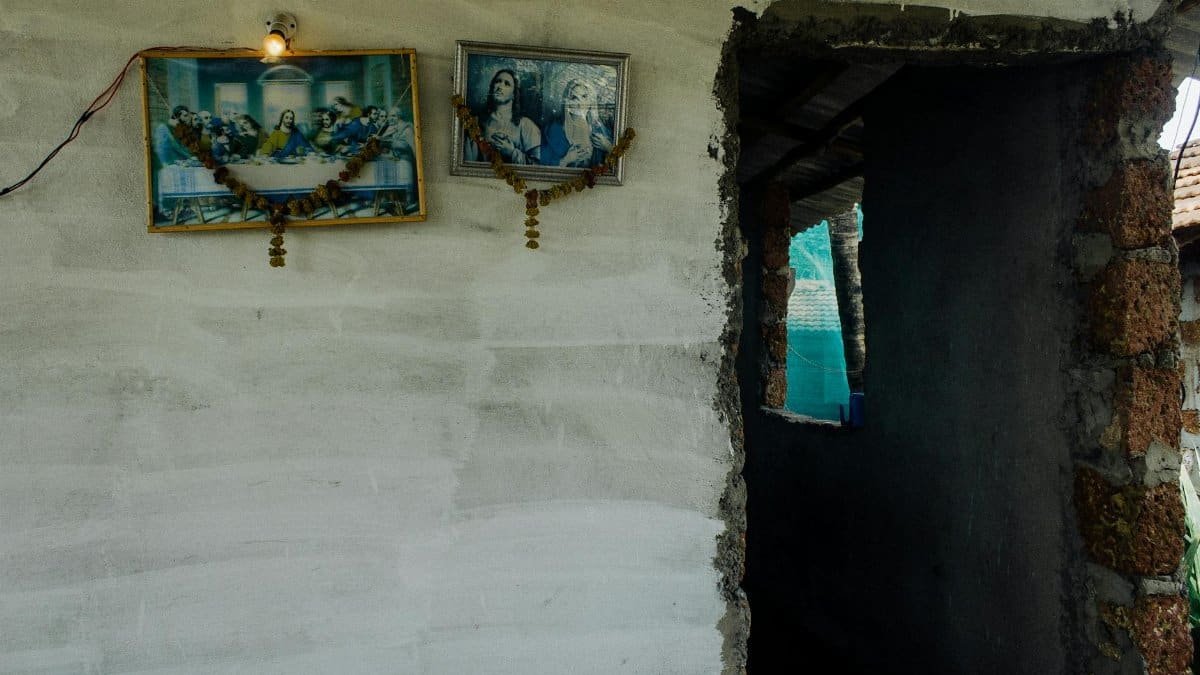 Exterior of aged desolate building with icons and glowing lamp on white stone wall near demolished doorway with bricks on street