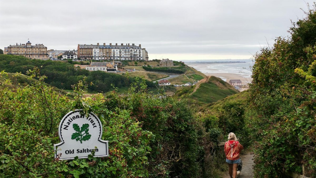 A person walks along a National Trust path in Old Saltburn, offering stunning coastal views.