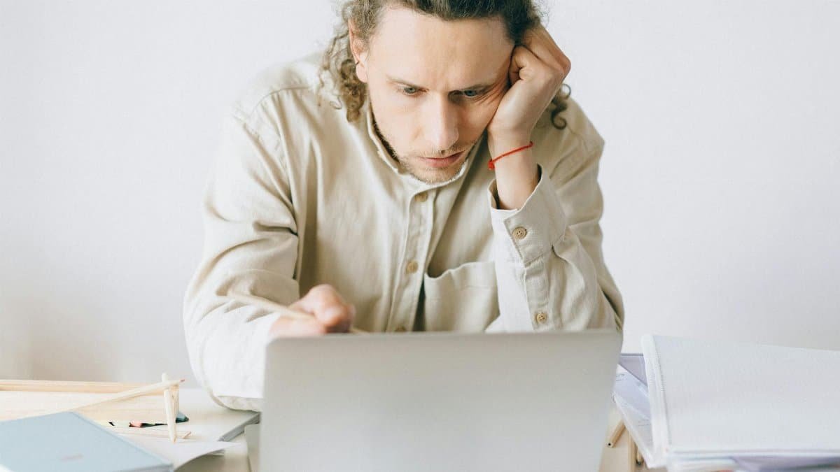 Adult man stressed at work, experiencing burnout while working on laptop at desk.