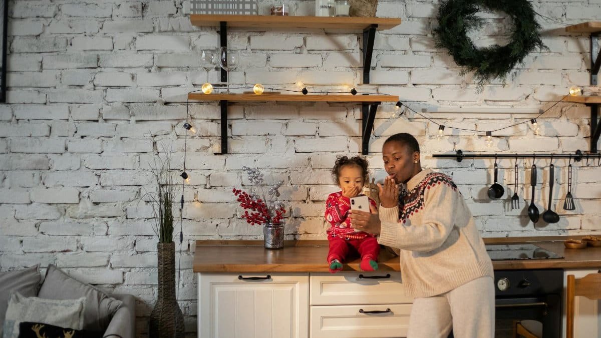 A joyful moment of a mother and child having a Christmas video call in a warmly decorated kitchen.