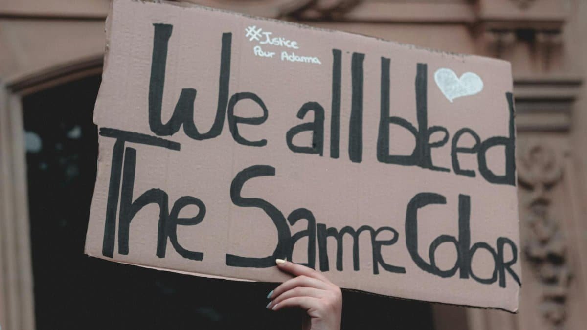 Sign at a protest reading: 'We all bleed the same color', promoting equality and justice.