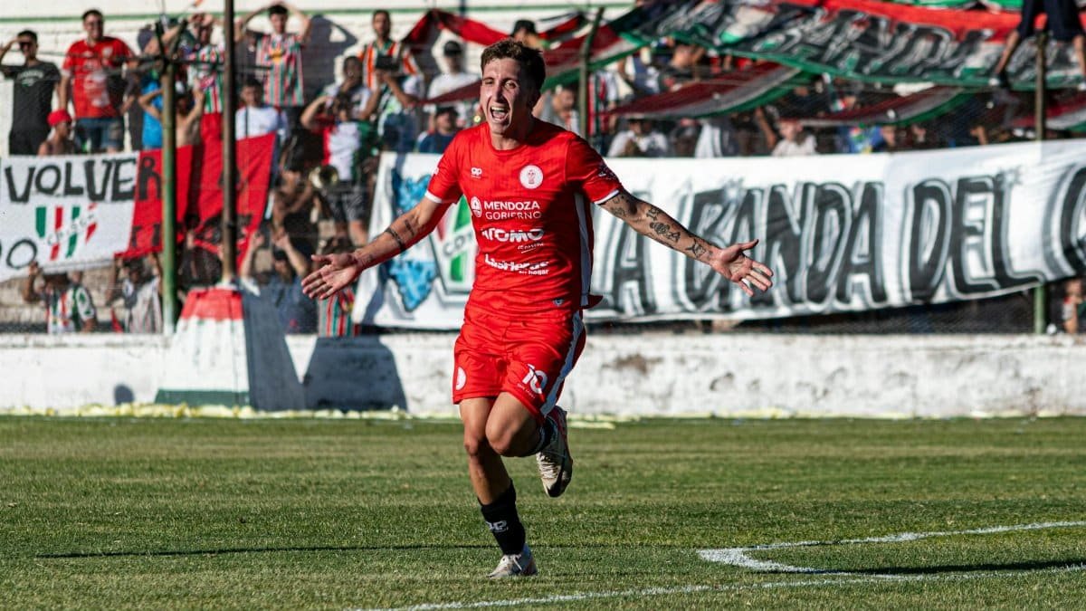Excited soccer player celebrates scoring a goal with cheering fans in background.