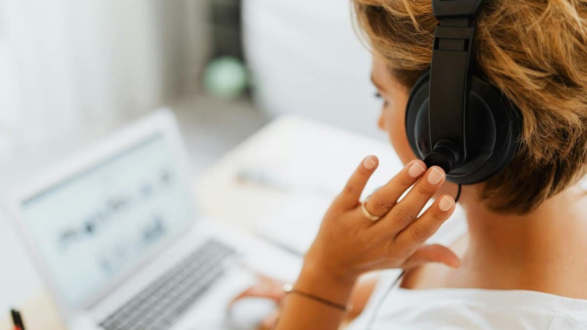 Woman at home using headphones and laptop for online work or video call.