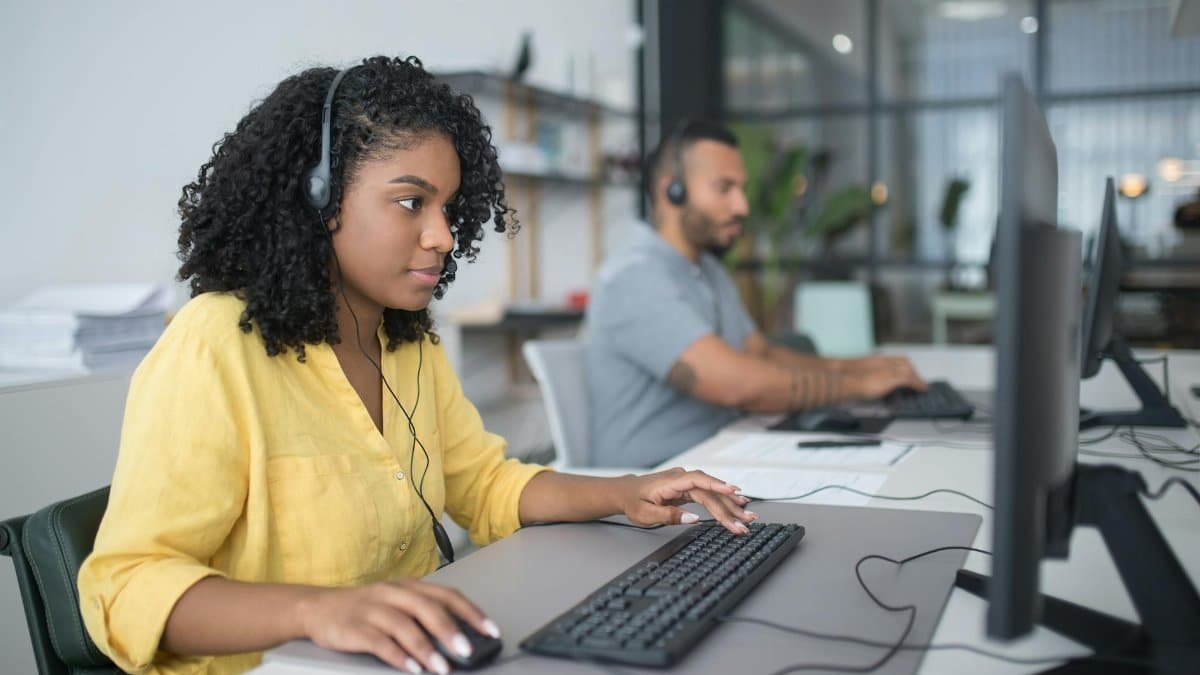 Two customer service agents working with headsets in a modern office setting.