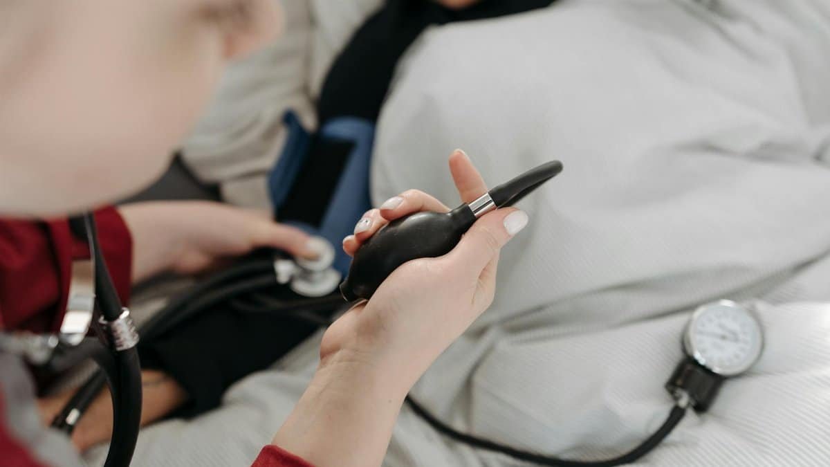 A healthcare professional uses a sphygmomanometer to check a patient's blood pressure at home.