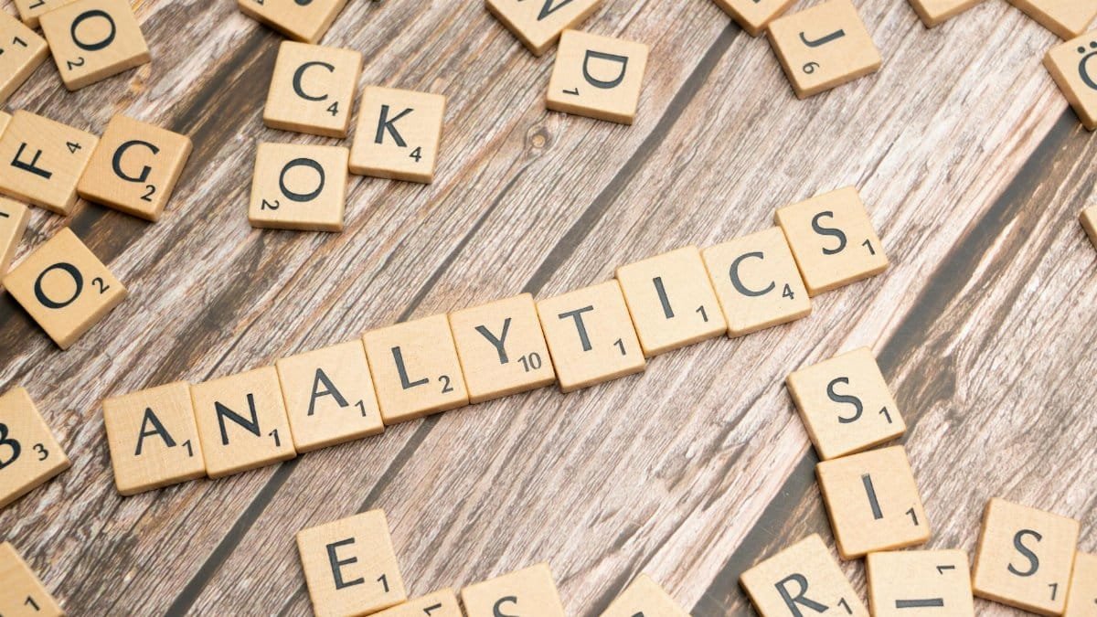 Scrabble tiles spelling 'Analytics' on a wooden surface, symbolizing data analytics concept.