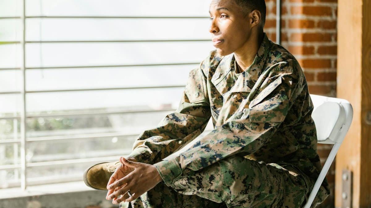 US veteran in uniform seated thoughtfully indoors, reflecting on mental health.