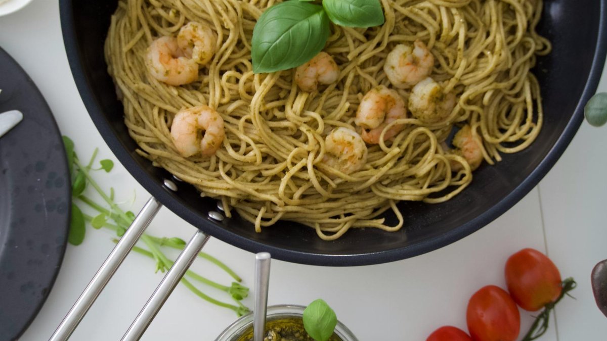 A top view of shrimp pesto pasta garnished with basil, perfect for culinary inspiration.