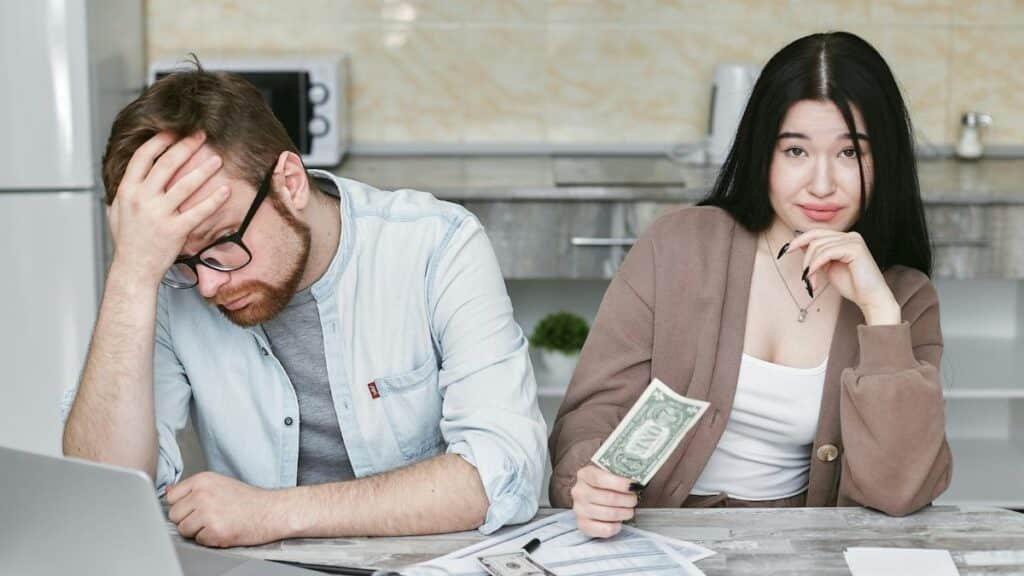 A couple managing their finances in a kitchen setting, showcasing money, debt, and budgeting challenges.