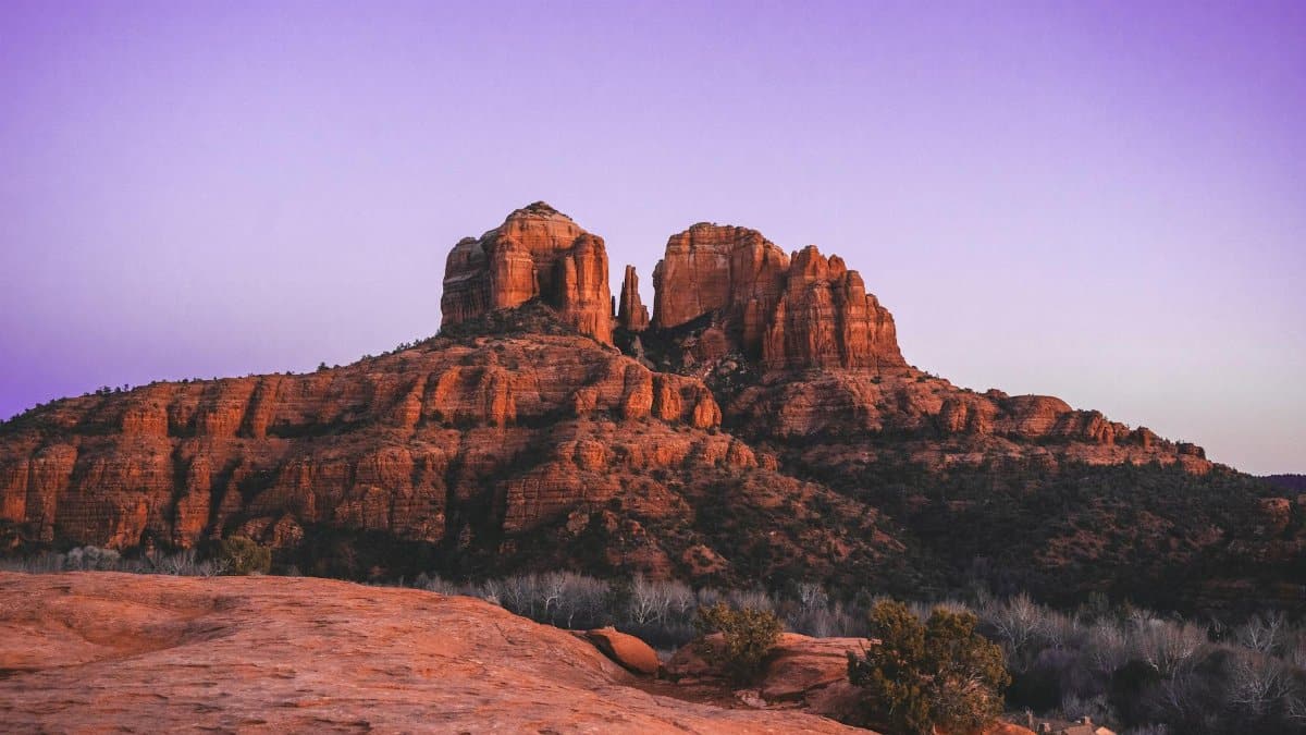 Dramatic view of Cathedral Rock in Sedona, AZ, with vibrant sunset hues.
