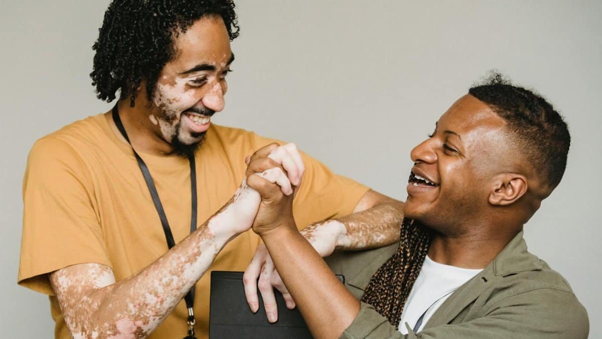 Two coworkers share a celebratory moment with a handshake, exuding joy and unity.