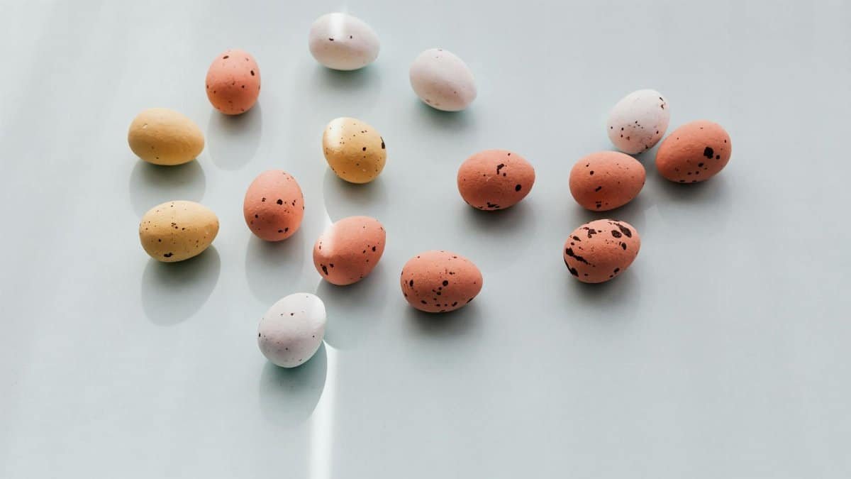 Pastel-colored Easter eggs with dotted patterns arranged on a light background, creating a minimalistic festive scene.
