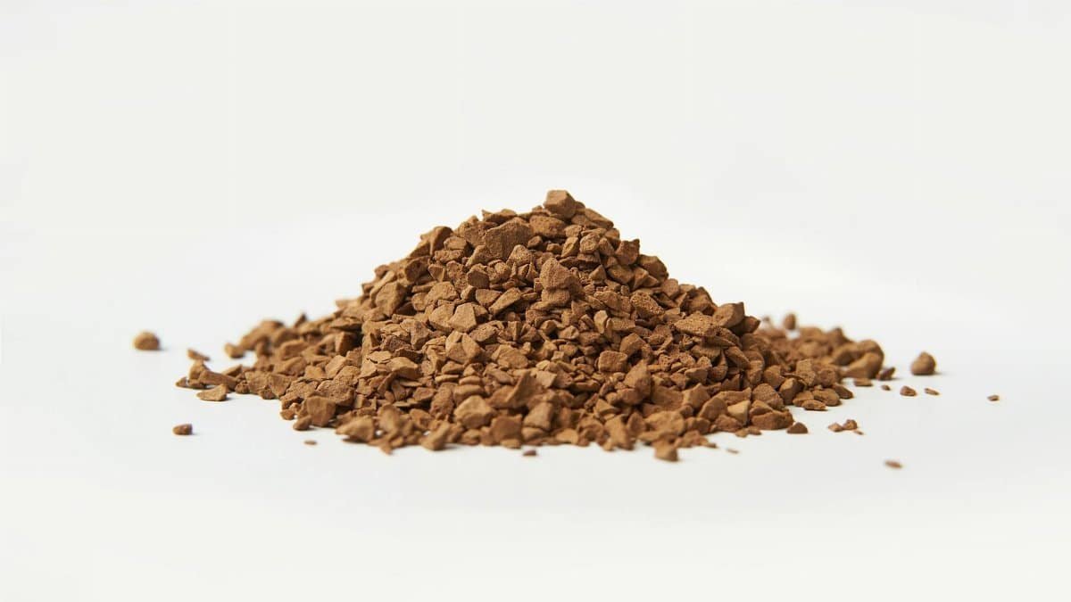 A close-up image of brown instant coffee granules on a white background.